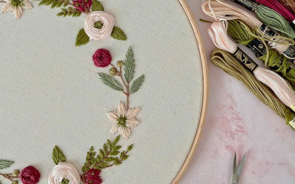 Close-up of hands hand-embroidering a floral design, representing custom patch craftsmanship